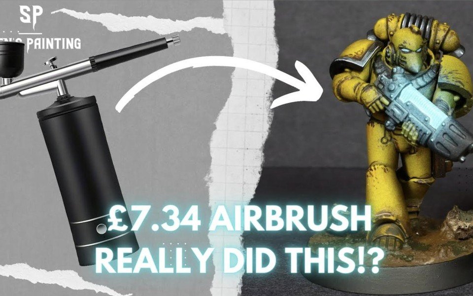 A cheap airbrush next to a painted yellow Space Marine miniature
